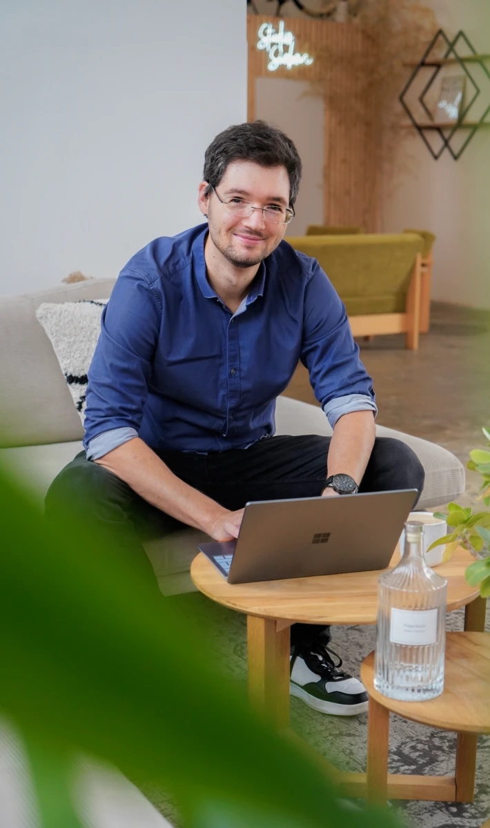 Junger Mann im Wohnzimmer mit einem Laptop arbeitet an der Betreuung einer Webseite.