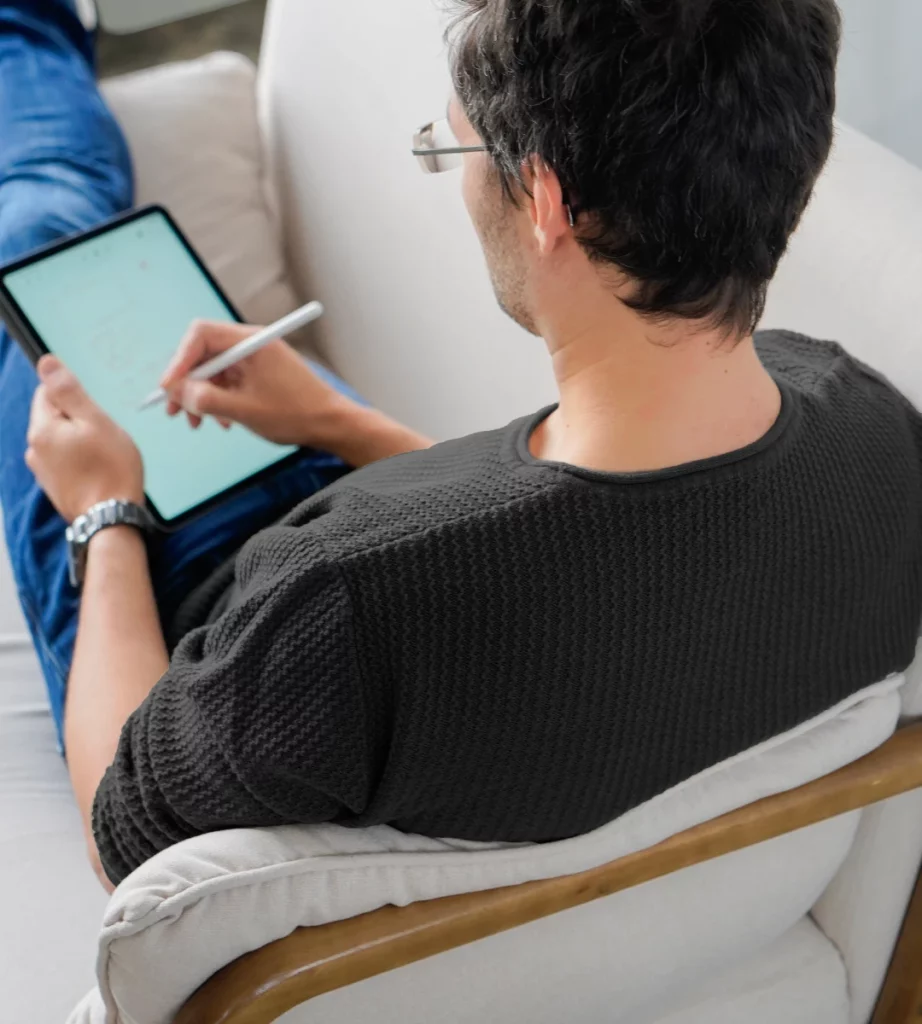 Junger Mann auf einem Sofa erstellt Wireframes auf dem iPad.